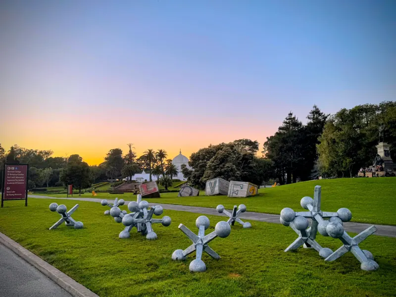 Ten steel jax sculptures across the Conservatory of Flowers lawn in Golden Gate Park at sunset